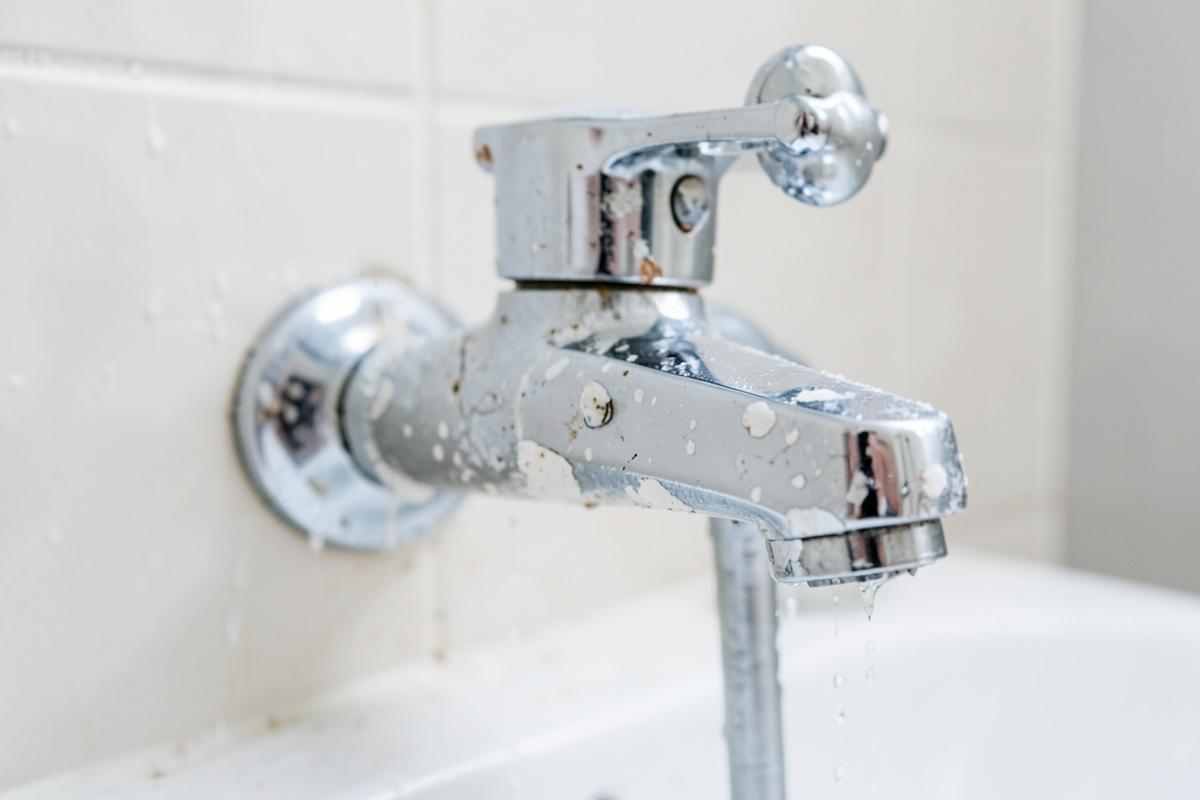 Chrome bathroom faucet with white mineral scale and water spots